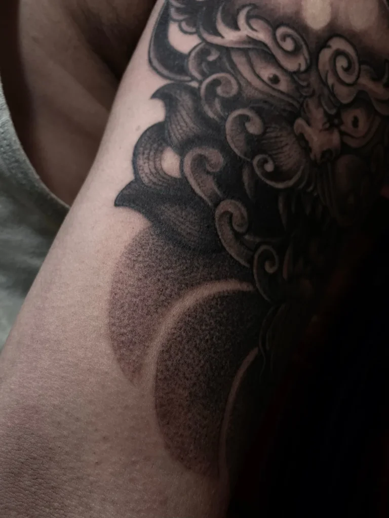 Detalle del sombreado con puntillismo de un tatuaje de león guardián en el brazo