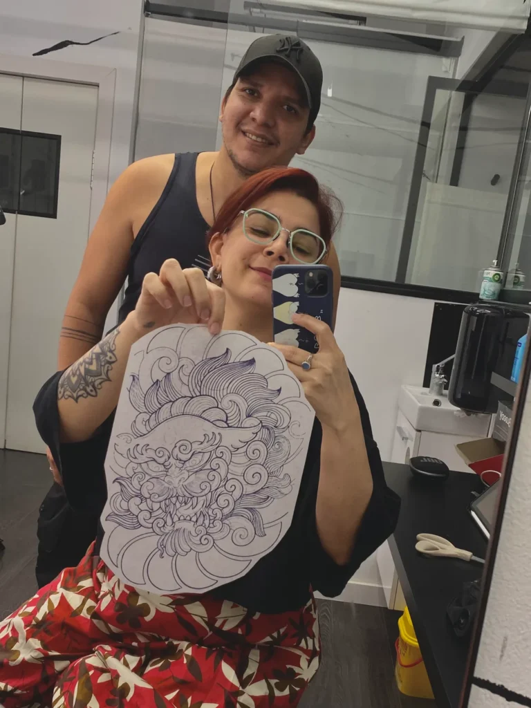 Frank Rojazz con Odalys mostrando el diseño de su tatuaje en Ochoa Ink, Valencia